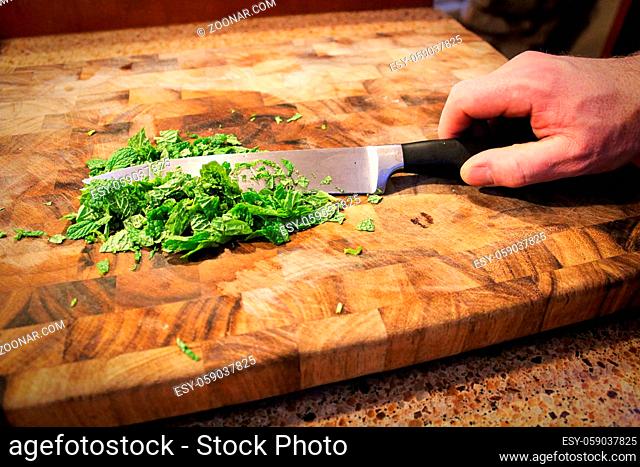 Closeup of a hand holding a knife cutting green mint