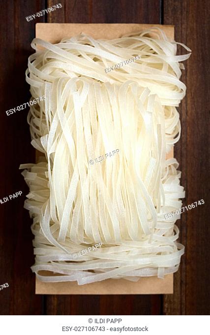 Raw rice flour noodles, photographed overhead on dark wood with natural light (Selective Focus, Focus on the top of the noodles)