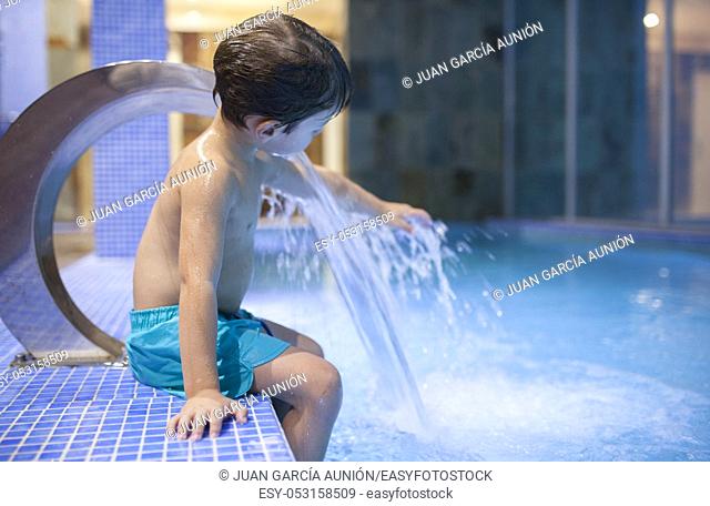 4 years boy playing with jets at indoor pool SPA. Selective focus