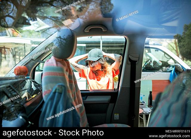 Woman wearing cap seen through car window