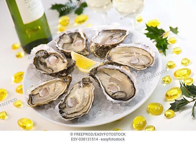 Oysters on ice and with a piece of lemon and wine bottle and glass
