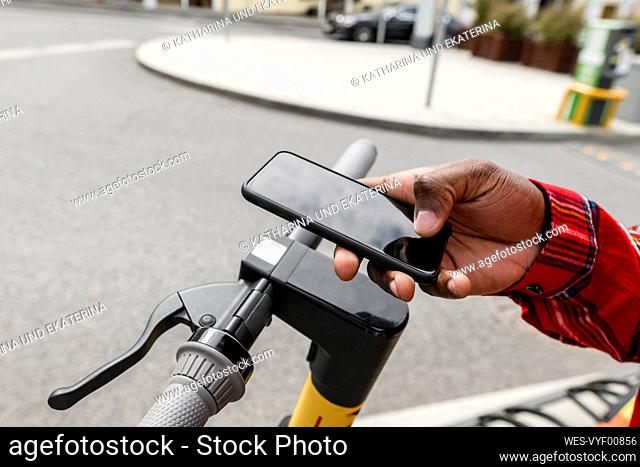 Man with push scooter using smart phone on street