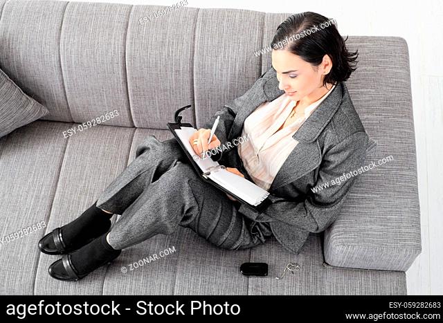 Young businesswoman sitting on sofa, working, overhead view