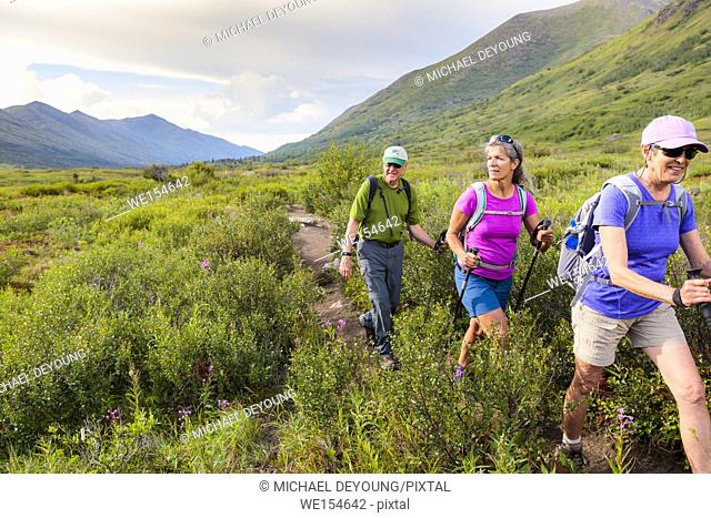 Three hikers hiking to Eagle Lake on South Fork Eagle River trail near Anchorage, Alaska