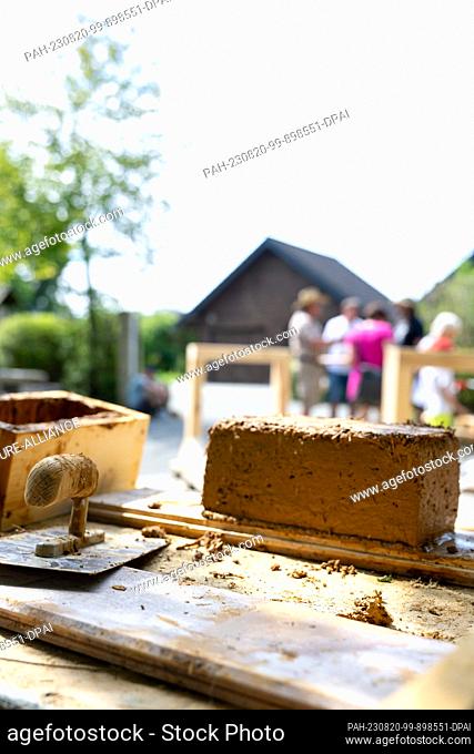 20 August 2023, Bavaria, Hallerstein: A freshly stamped adobe brick and tools lie on a table. Nearly 60 regional and almost forgotten crafts are presented at...