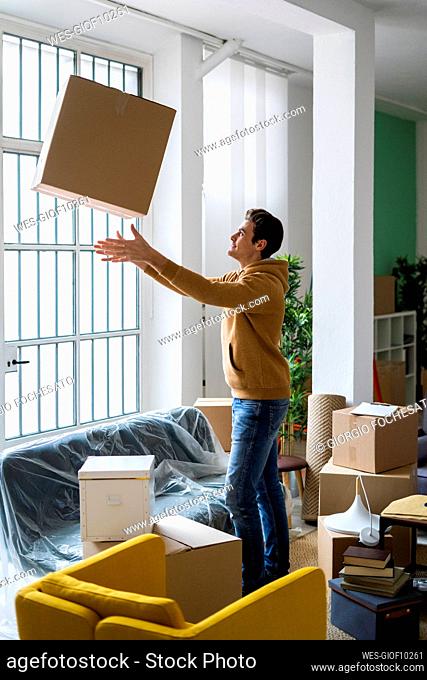 Playful young man throwing cardboard box while moving into new home