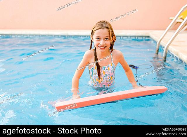 Smiling girl with swimming float in pool