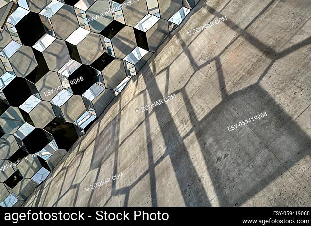 Shiny patterned wall of Harpa Hall in Reykjavik in Iceland. Sun shines onto it and creates shadows on the concrete wall. Horizontal