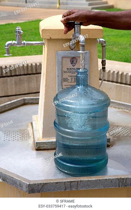 Man fills a jug at a fountain with mineral springs drinking water in Hot Springs National Park, Arkansas, USA