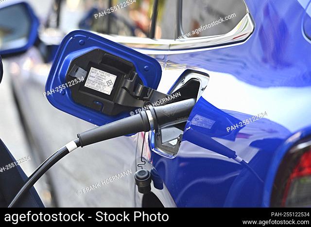 Dispensing nozzle for hydrogen in front of the open fuel filler flap. H2 gas, hydrogen, fuel cell. Opening of mobile hydrogen filling station and tank...