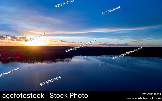 Aerial view of a beautiful and dramatic sunset over a forest lake reflected in the water, landscape drone shot. Blakheide, Beerse, Belgium