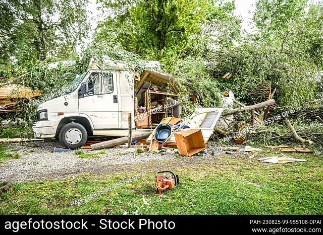 25 August 2023, Bavaria, Lindau: Fallen trees and branches lie on a caravan at a campsite. The previous night, a severe thunderstorm had passed over the...