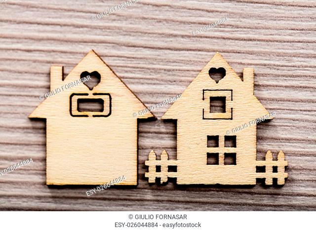 a couple of figures representing wooden little houses on a wooden bacground with a fence and a heart shaped window
