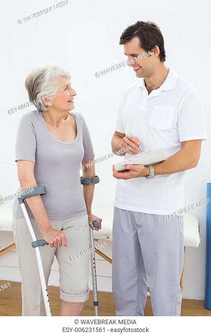 Therapist discussing reports with a disabled senior patient
