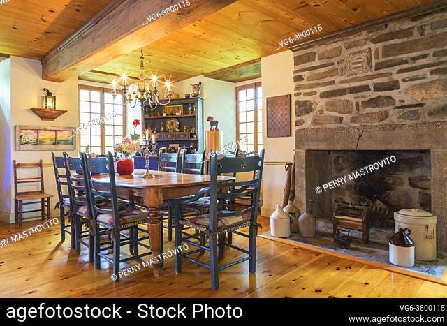 Pine wood dining table with two captain's armchairs and six high back chairs, antique pine wood buffet and natural stone wood burning fireplace in dining room...