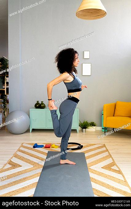 Woman practicing yoga on one leg at home