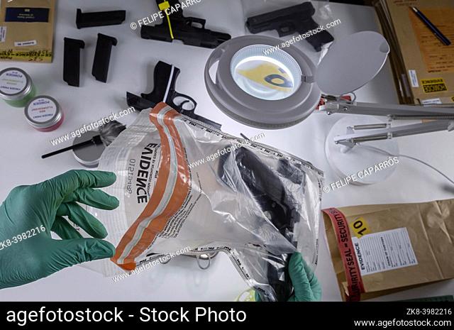 Police scientist pulls firearm evidence out of bag for crime lab research, conceptual image