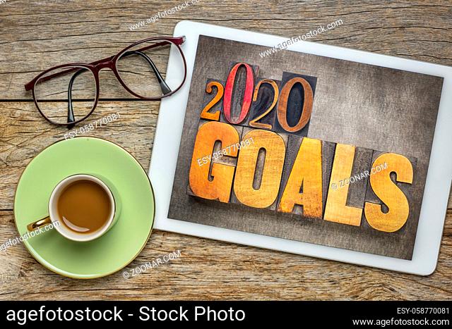 2020 goals - New Year resolution concept - word abstract in vintage letterpress wood type blocks against grunge metal background on screen of a digital tablet...