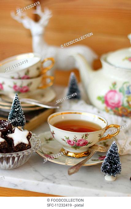A cup of tea with a rose pattern and Christmas biscuits