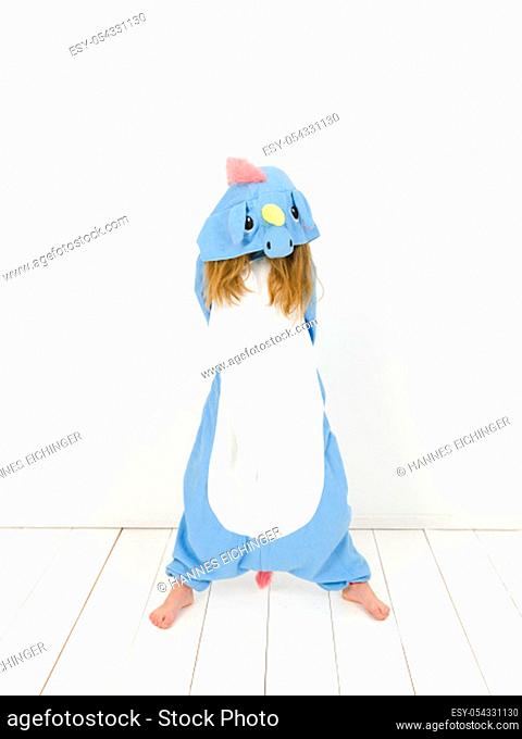pretty blonde girl with cozy blue unicorn costume is posing in the studio in front of white wall