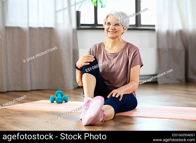 smiling senior woman exercising on mat at home