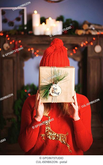 Woman holding christmas present in front of face