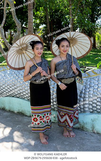 Two high school girls in traditional dresses and with parasols posing on the staircase of a temple in the UNESCO world heritage town of Luang Prabang in Central...