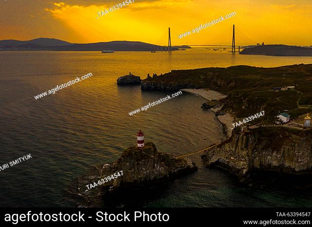 RUSSIA, VLADIVOSTOK - OCTOBER 15, 2023: A view of the lighthouse on the Basargin Cape and a cable-stayed bridge across the Eastern Bosphorus Strait to Russky...