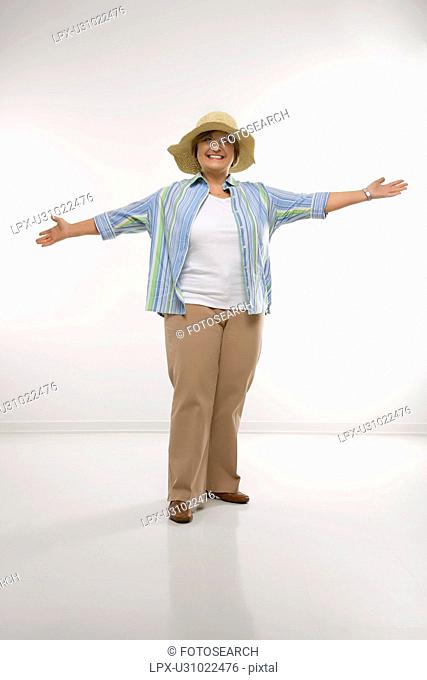 Caucasian middle aged woman wearing straw hat holding arms outstretched