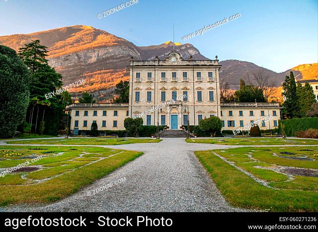 Ancient villa Sola Cabiati in Tremezzo, on Lake Como. Lombardy, Italy. Amazing mountain background in yellow rays of sunset