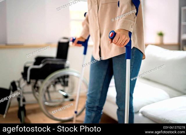 Hurt Leg Using Crutches Near Wheelchair At Home