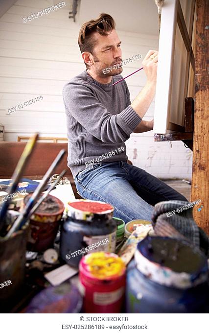 Male Artist Working On Painting In Studio