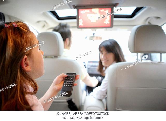 Family travelling, girl watching DVD in car