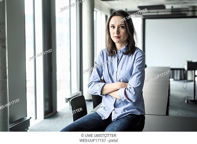 Portrait of serious businesswoman sitting on conference table in office