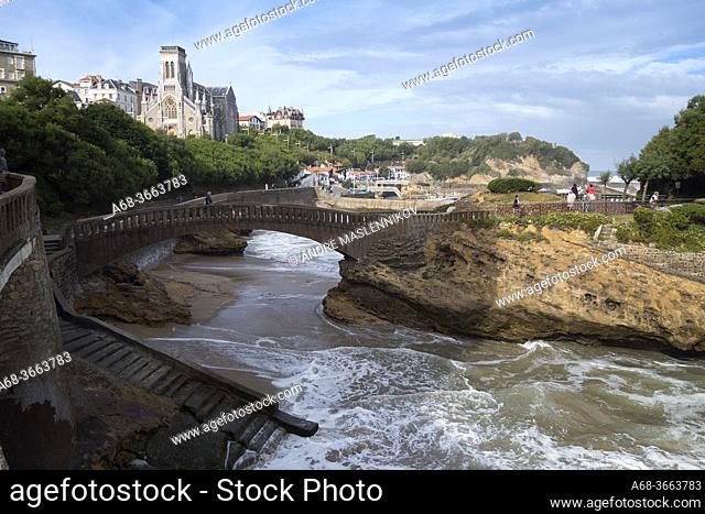 Bridge to the Rocher du Basta rock on the beach in Biarritz, France. Crypte Sainte Eugénie behind. . Photo: André Maslennikov