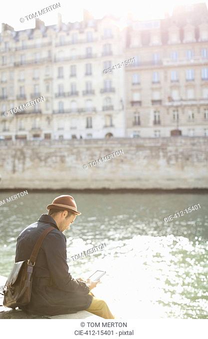 Businessman using cell phone along Seine River, Paris, France