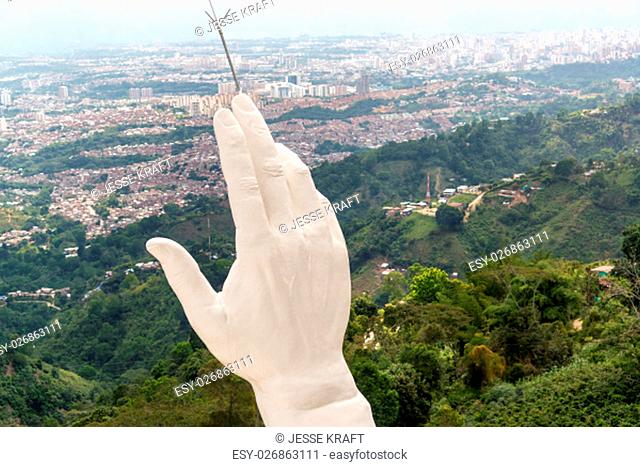 View of the hand of the El Santisimo statue in Floridablanca, Colombia with Bucaramanga visible in the background