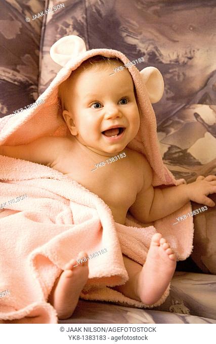 Happy Emotional Eight Month Old Infant Girl Sitting in Bathrobe