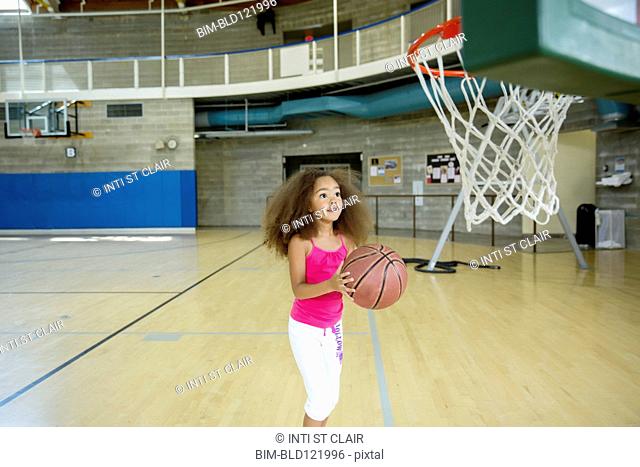 Mixed race girl playing basketball on court