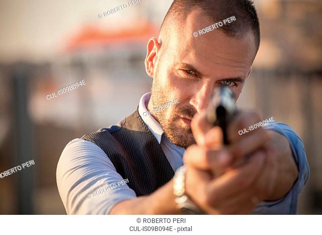 Close up of man poised with handgun looking at camera
