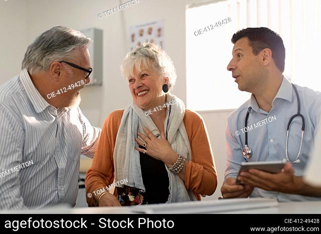 Doctor meeting with happy senior couple in doctors office