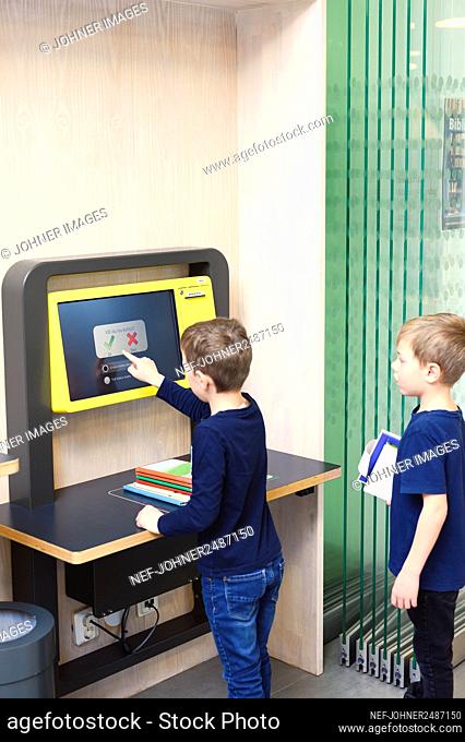 Boys using self service point in library