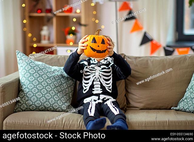 boy in halloween costume with jack-o-lantern