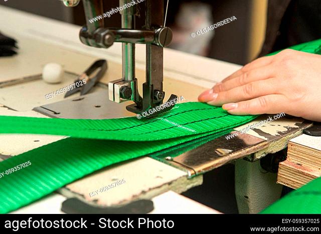 Industrial sewing machine sews a webbing sling. Manufacture of textile slings and tie straps