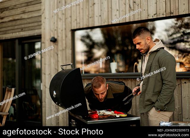 Male friends preparing food on barbecue