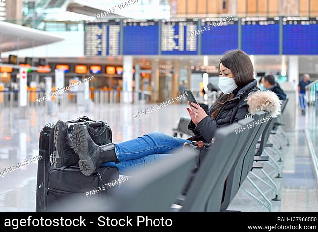 Themed picture trips in times of the corona pandemic. Young woman with face mask, mask with her suitcase, luggage at Munich Airport on December 6th, 2020