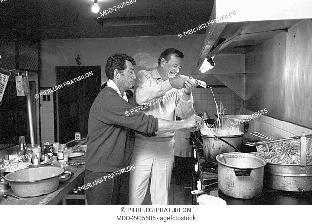 American actors Dean Martin (Dino Paul Crocetti) and John Wayne (Marion Mitchell Morrison) having fun by cooking spaghetti in a break during the shooting of the...