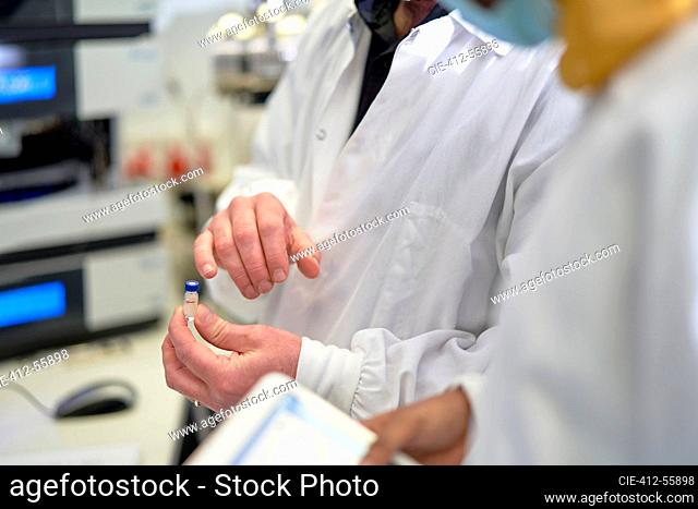 Close up scientists examining vial in laboratory