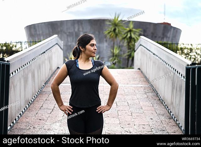 Young woman during workout at bridge looking sideways