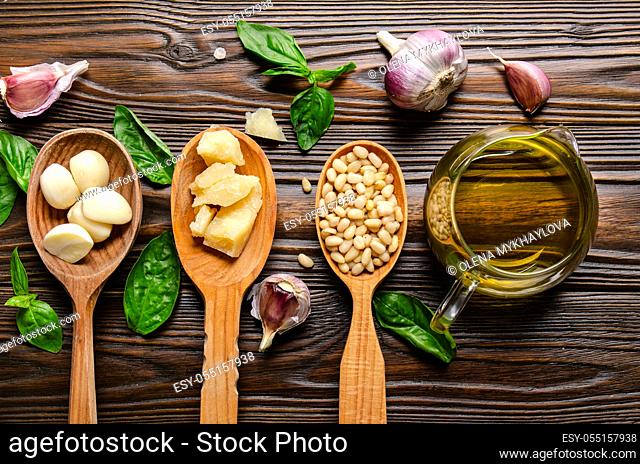 Flat lay view at wooden spoons with food ingredients for pesto genovese sauce on kitchen table